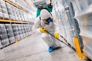 worker in white hazmat suit spraying chemicals inside a facility